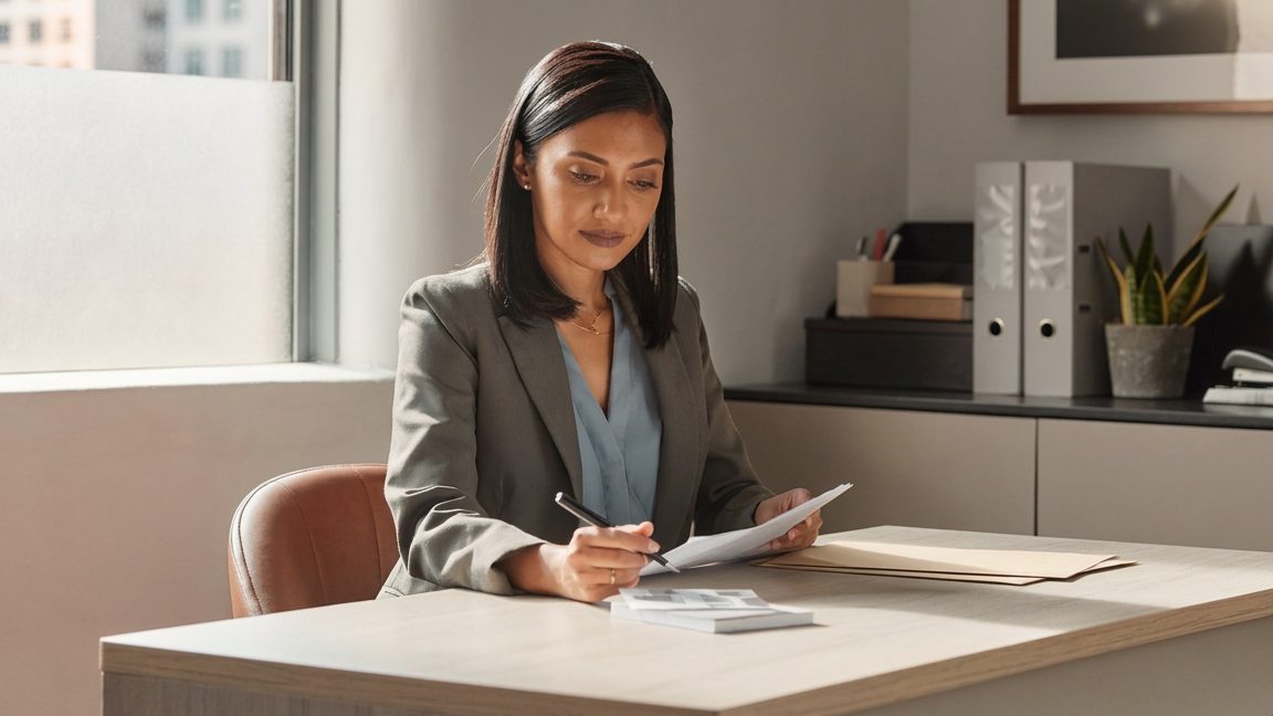 An attorney at a plain desk reviewing paperwork in a small office